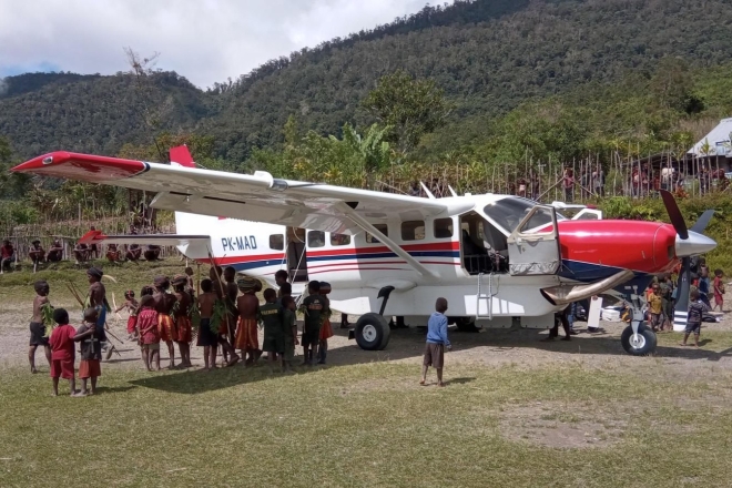 Kinder stehen neugierig um ein MAF-Flugzeug